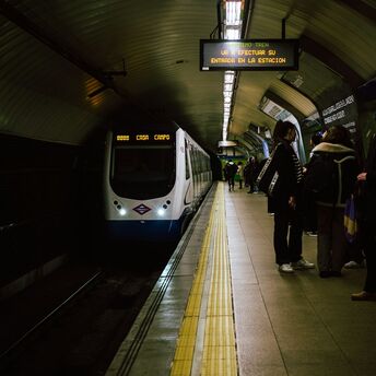 The Madrid subway train stops at the station, and passengers are waiting on the platform