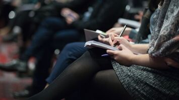 A group of people seated, taking notes during a conference or seminar