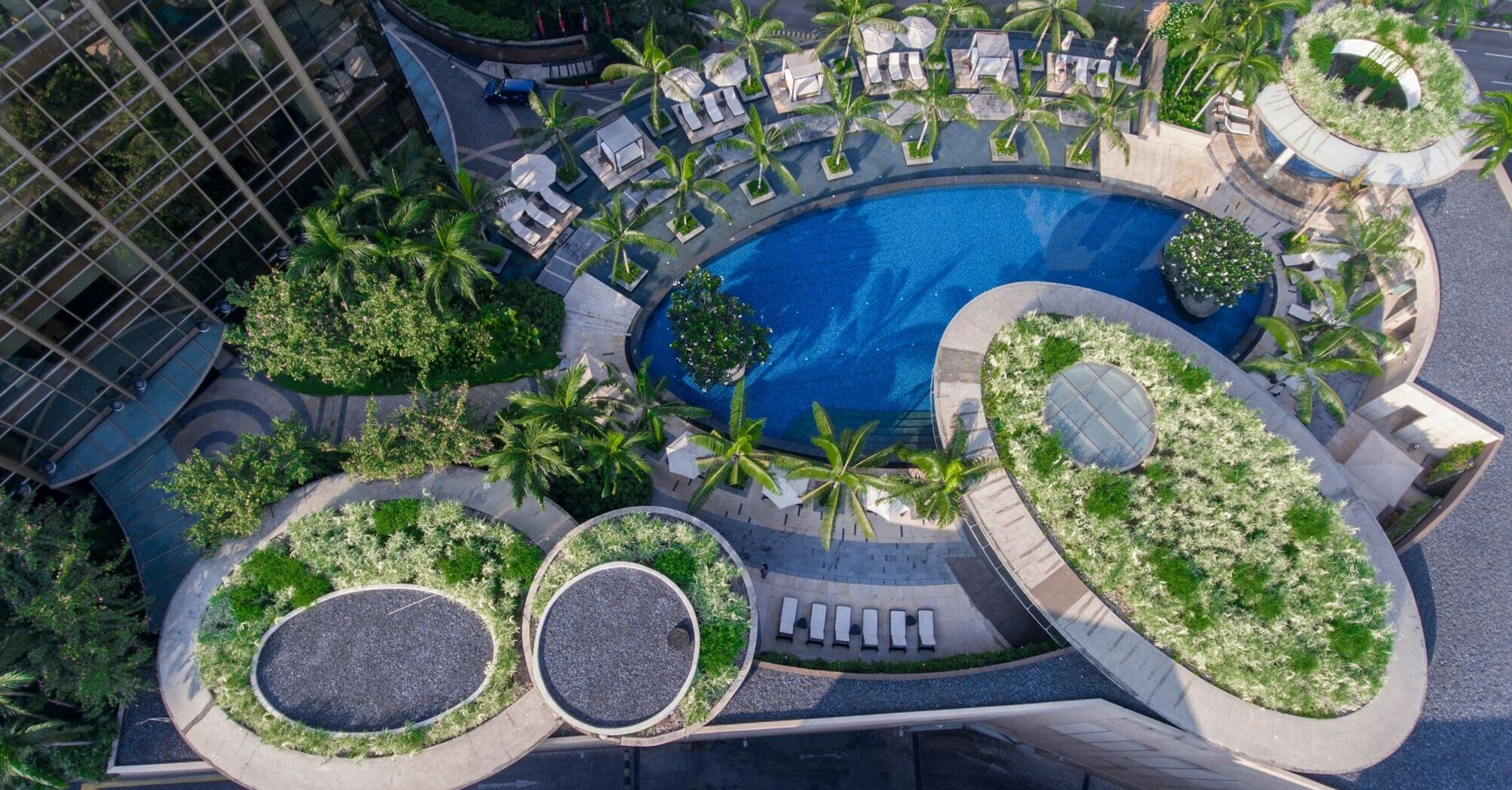 Overhead view of the luxurious pool area at Grand Hyatt Kuala Lumpur surrounded by lush greenery and modern architecture