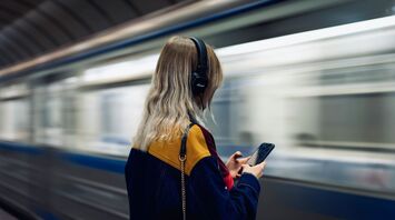 Woman enjoys music while framed by the backdrop of a high-speed train in motion