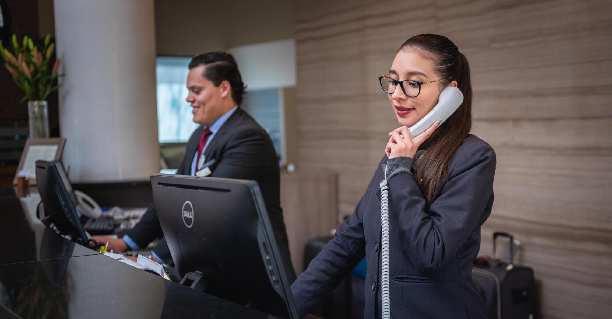 The hotel staff works at the front desk, handling reservations, and interacting with guests
