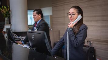 The hotel staff works at the front desk, handling reservations, and interacting with guests
