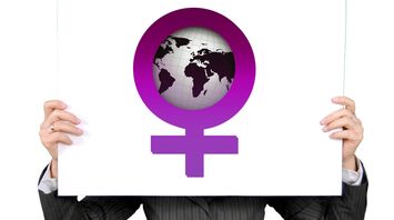 Person holding a sign with a female gender symbol incorporating a globe on a white background