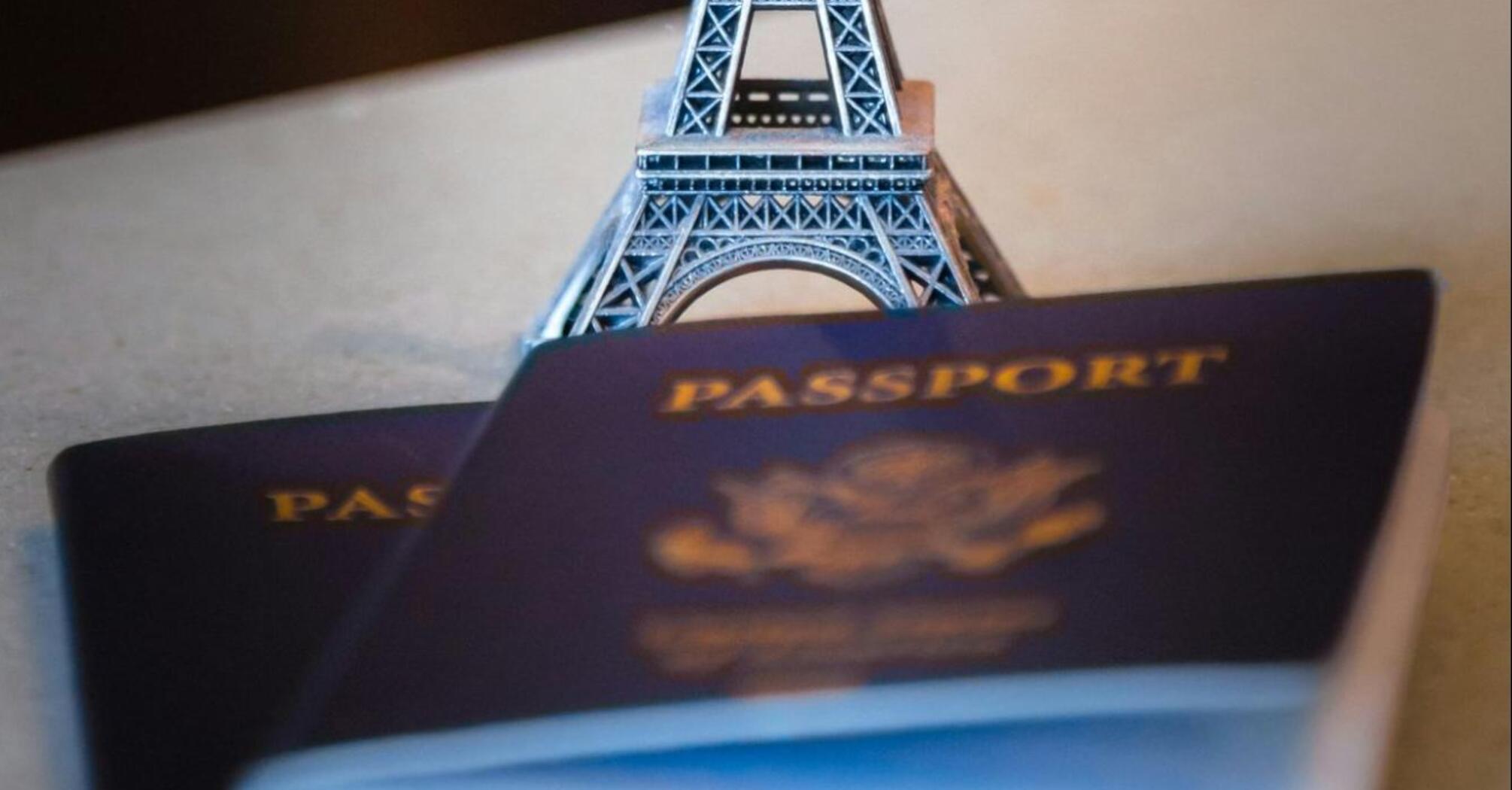 A miniature Eiffel Tower stands on top of two passports, symbolizing the impact of new travel regulations on French tourists