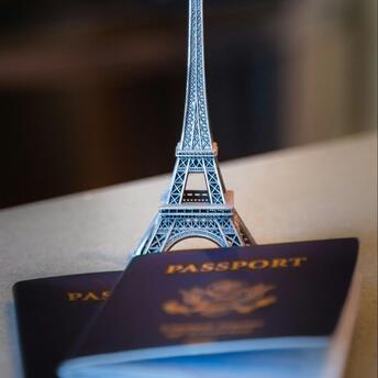 A miniature Eiffel Tower stands on top of two passports, symbolizing the impact of new travel regulations on French tourists