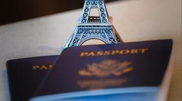 A miniature Eiffel Tower stands on top of two passports, symbolizing the impact of new travel regulations on French tourists