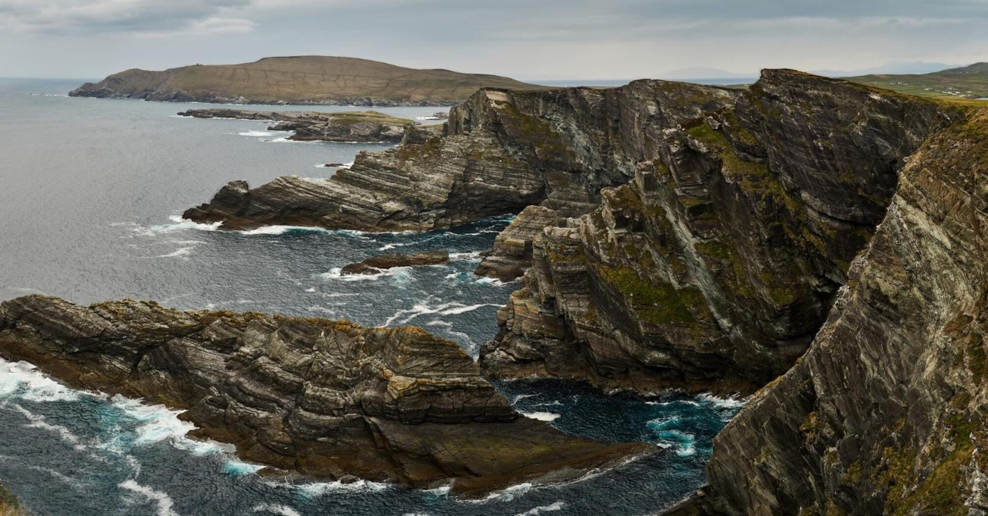 A panoramic view of a rugged coastline with jagged cliffs overlooking the sea