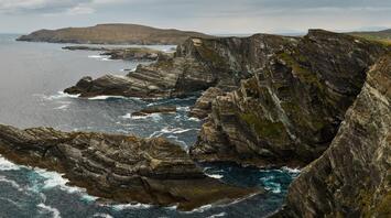 A panoramic view of a rugged coastline with jagged cliffs overlooking the sea