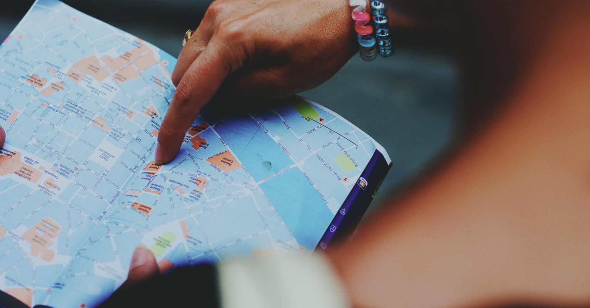 A person points to a location on a map, helping navigate through city streets