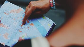A person points to a location on a map, helping navigate through city streets