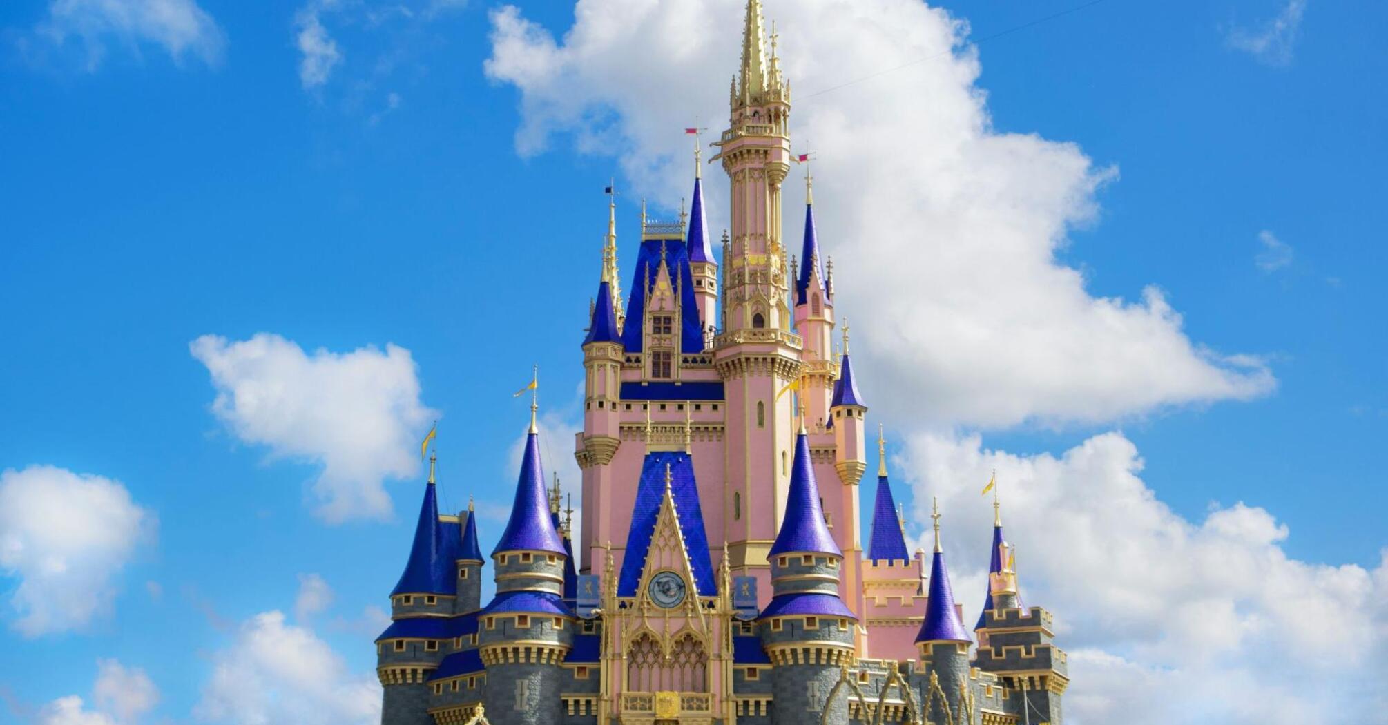 Castle with blue spires in a theme park against a blue sky with white clouds