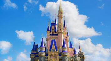 Castle with blue spires in a theme park against a blue sky with white clouds