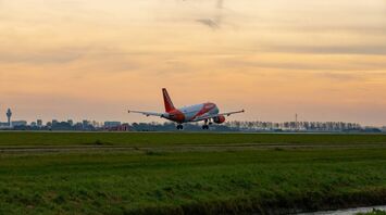 An easyJet plane taking off at sunset near a city