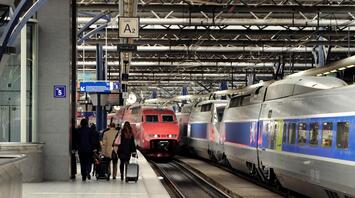 Passengers walking toward modern high-speed trains at a busy European railway station