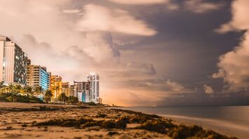 Night view of beachfront skyscrapers under a cloudy sky