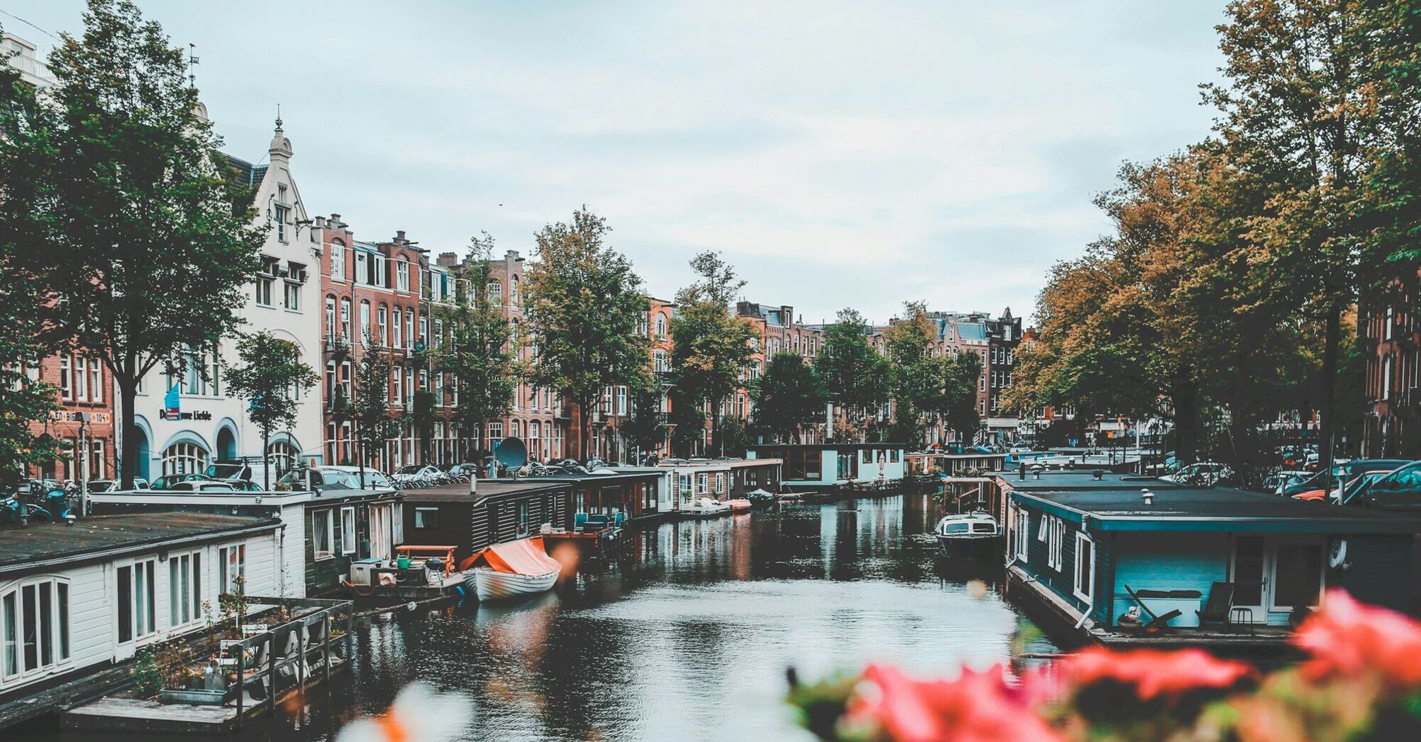 Amsterdam's picturesque canal with houseboats and historic buildings lining the water on a cloudy day