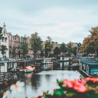 Amsterdam's picturesque canal with houseboats and historic buildings lining the water on a cloudy day