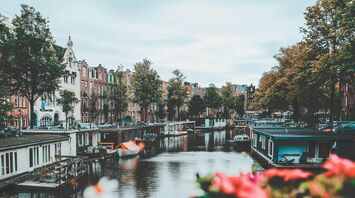 Amsterdam's picturesque canal with houseboats and historic buildings lining the water on a cloudy day