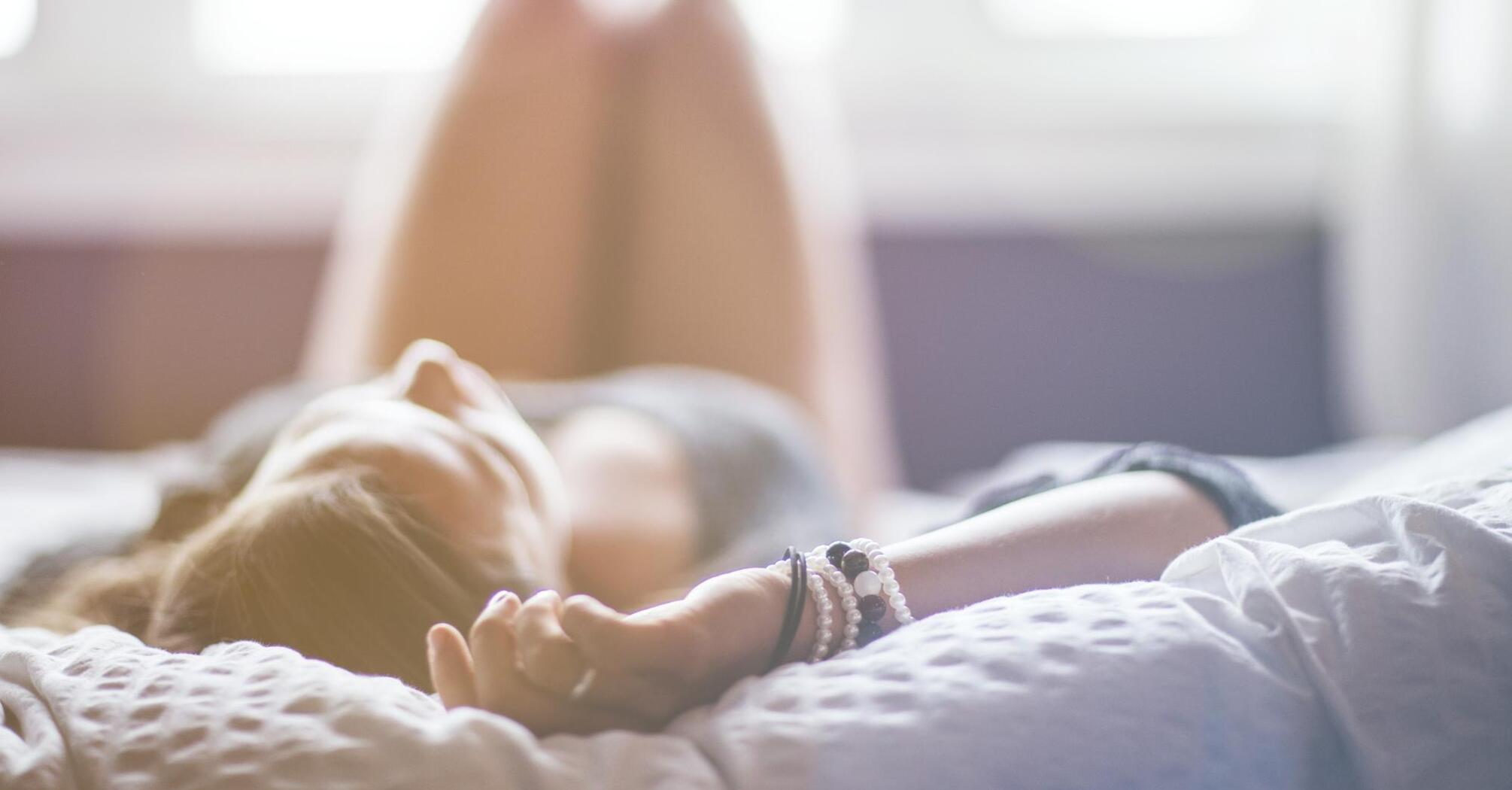 A woman relaxing peacefully in a bright, airy bedroom