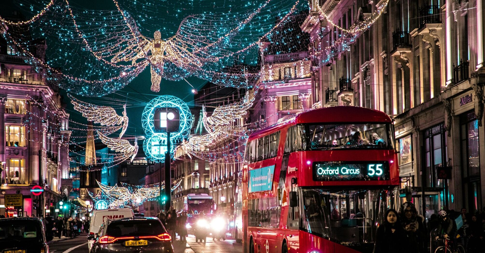 London’s Oxford Circus decorated with festive Christmas lights, featuring red double-decker buses and bustling evening traffic