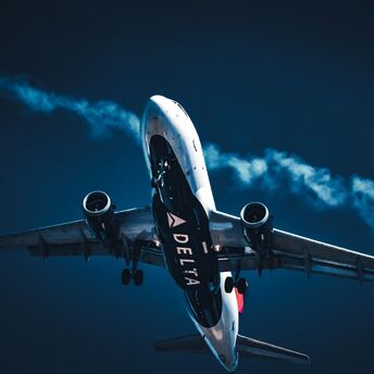 A Delta Airlines plane soaring through the sky with a trail of condensation