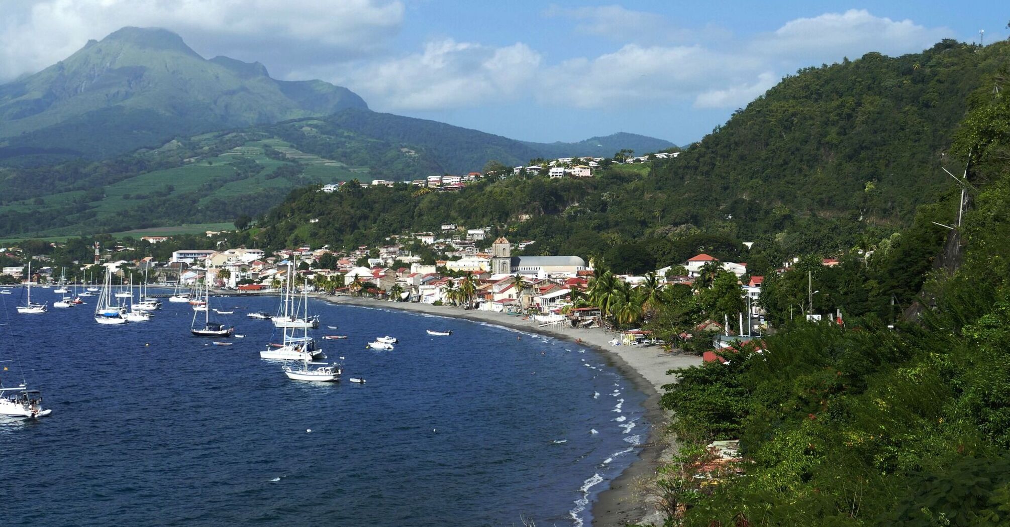 Coastal town in Martinique with boats and mountains in the background