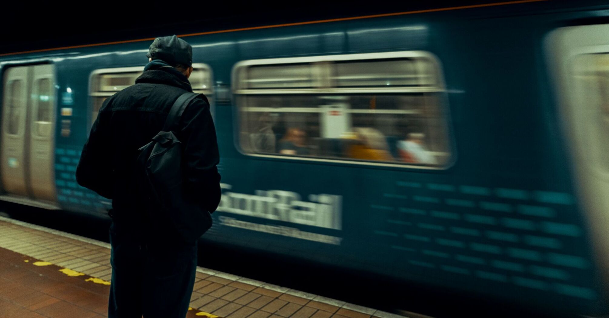 A person waits on the platform as a ScotRail train passes by at a station