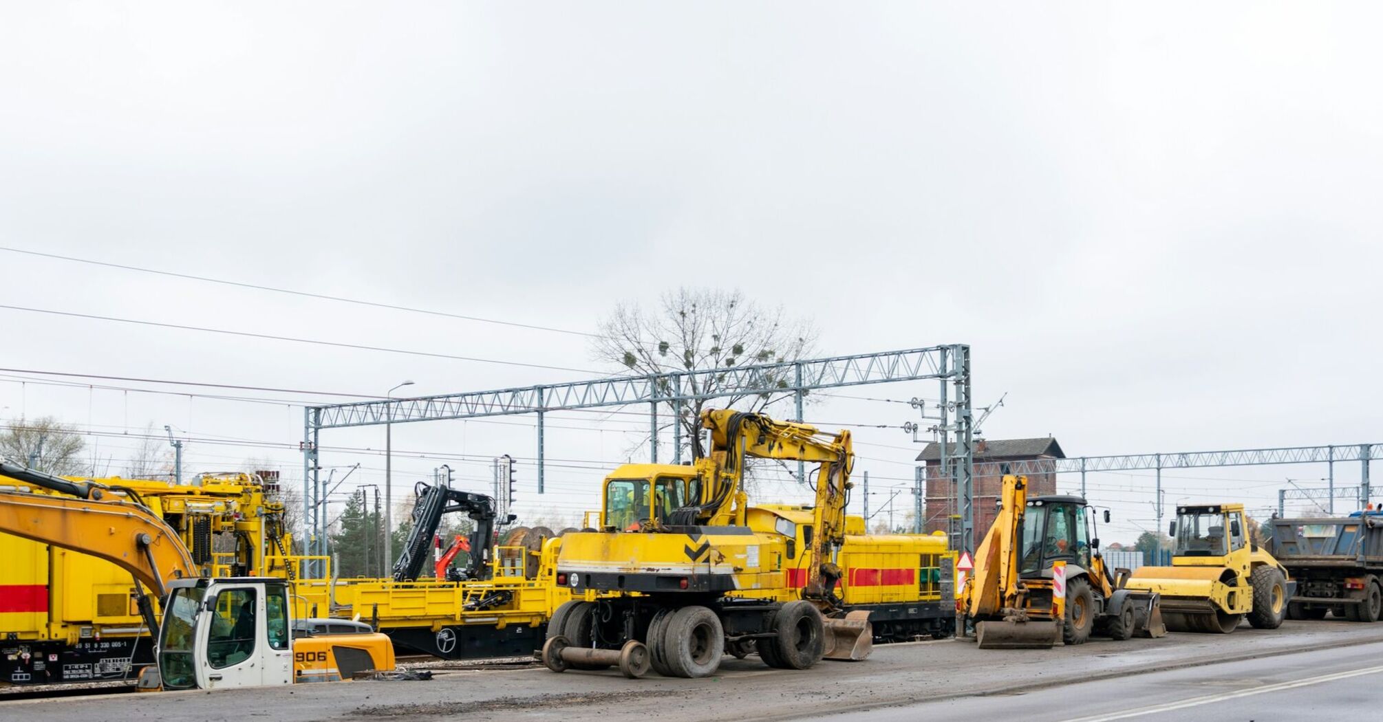 Construction equipment at a railway site with overhead electrical lines visible, used for rail infrastructure upgrades