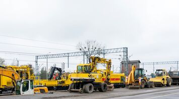 Construction equipment at a railway site with overhead electrical lines visible, used for rail infrastructure upgrades