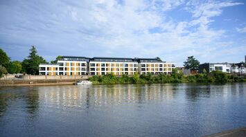 A view of modern riverside apartments next to the River Trent, reflecting on the water under a clear sky
