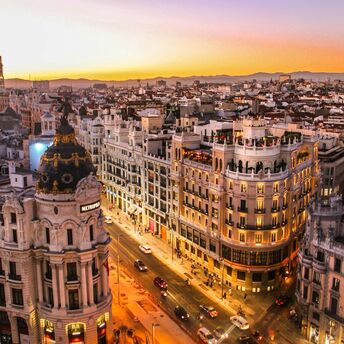 Aerial view of Madrid cityscape at sunset, featuring the Metropolis building and surrounding architecture