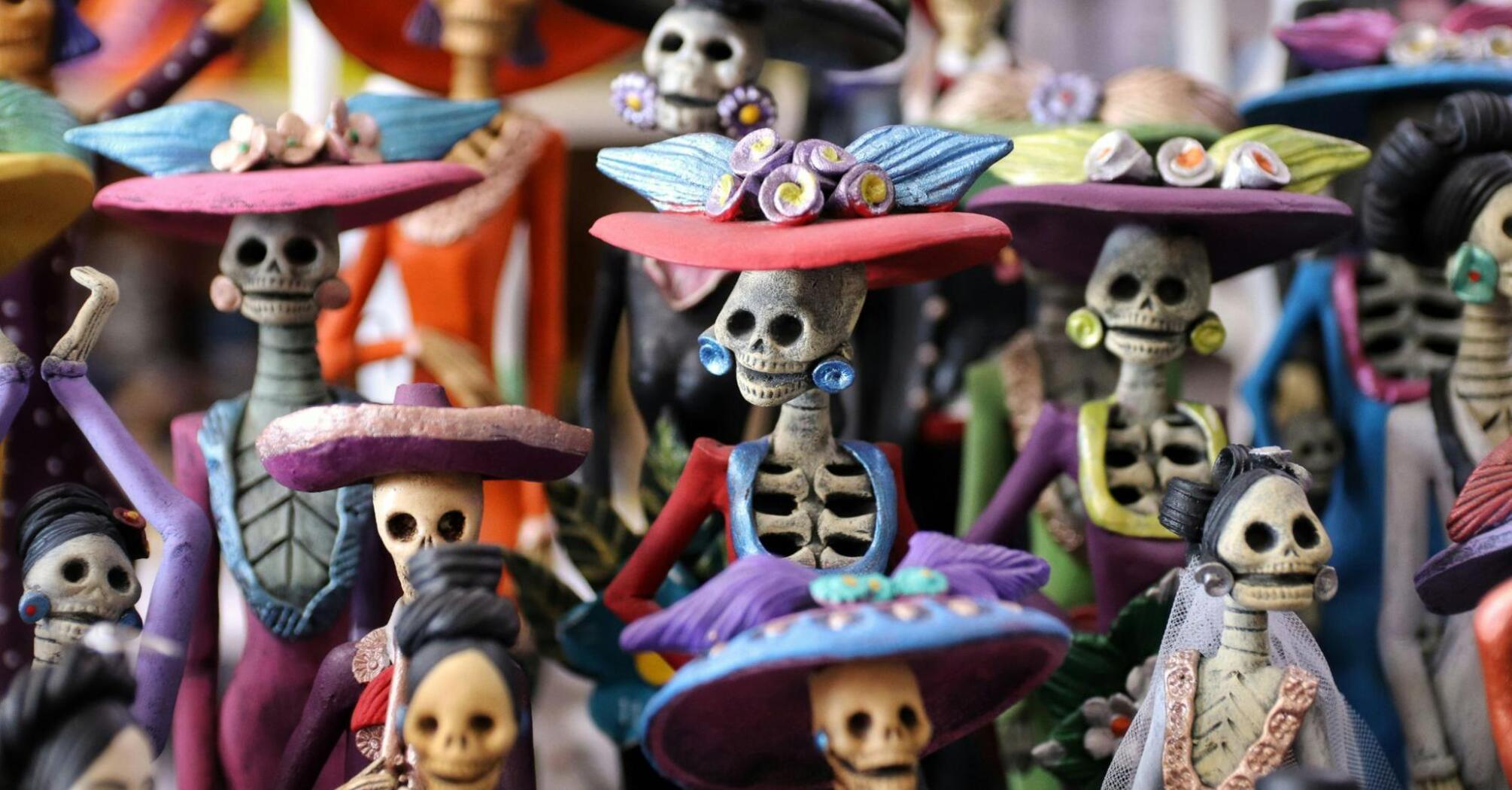 A colorful display of traditional Mexican Día de los Muertos figurines dressed in vibrant attire with skull faces