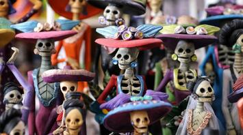 A colorful display of traditional Mexican Día de los Muertos figurines dressed in vibrant attire with skull faces