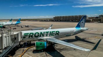 Frontier Airlines plane parked at the airport gate under a bright blue sky