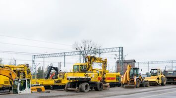 Construction vehicles and equipment at a rail maintenance site near overhead railway lines