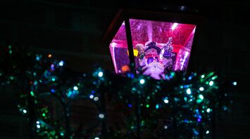 Festive snowman figurine in a lantern surrounded by glowing holiday lights