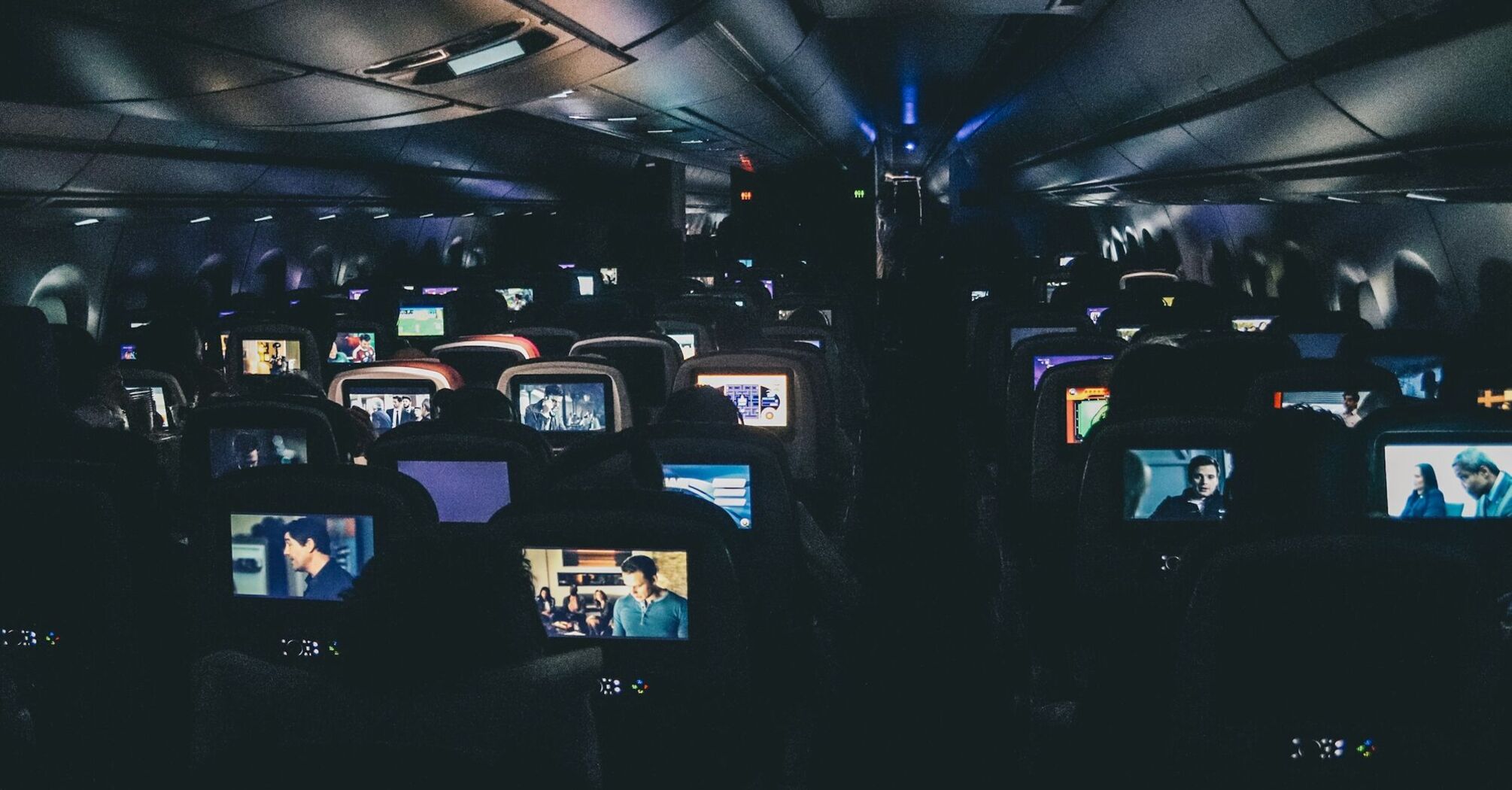 Passengers watching films on in-flight entertainment screens during a night flight