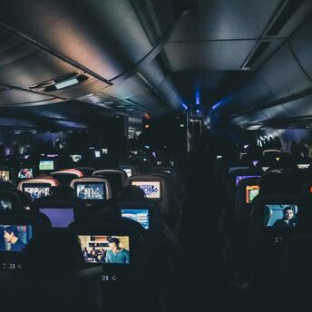 Passengers watching films on in-flight entertainment screens during a night flight