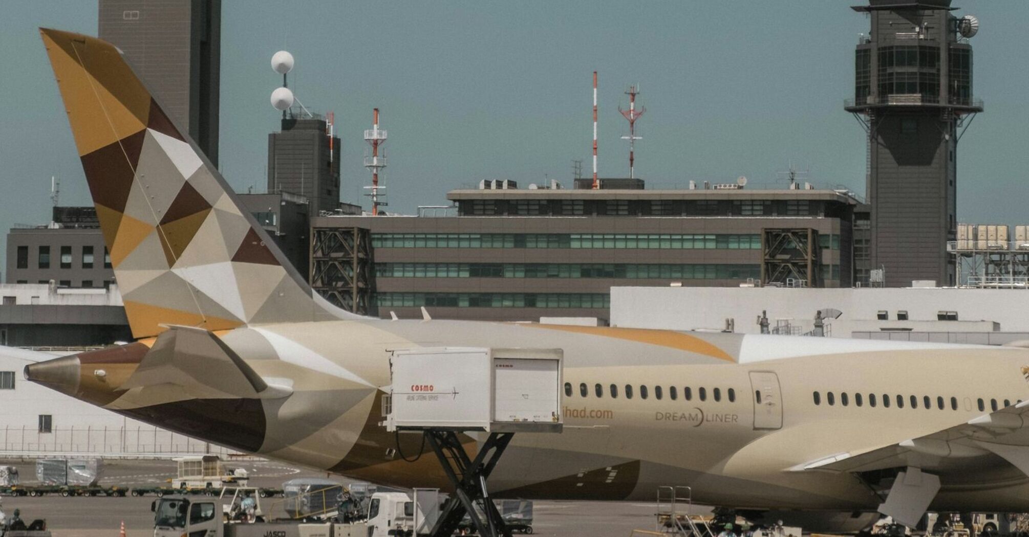 Etihad Airways aircraft at the airport being loaded with cargo, with ground staff and airport vehicles in the foreground