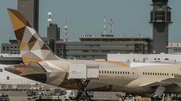 Etihad Airways aircraft at the airport being loaded with cargo, with ground staff and airport vehicles in the foreground