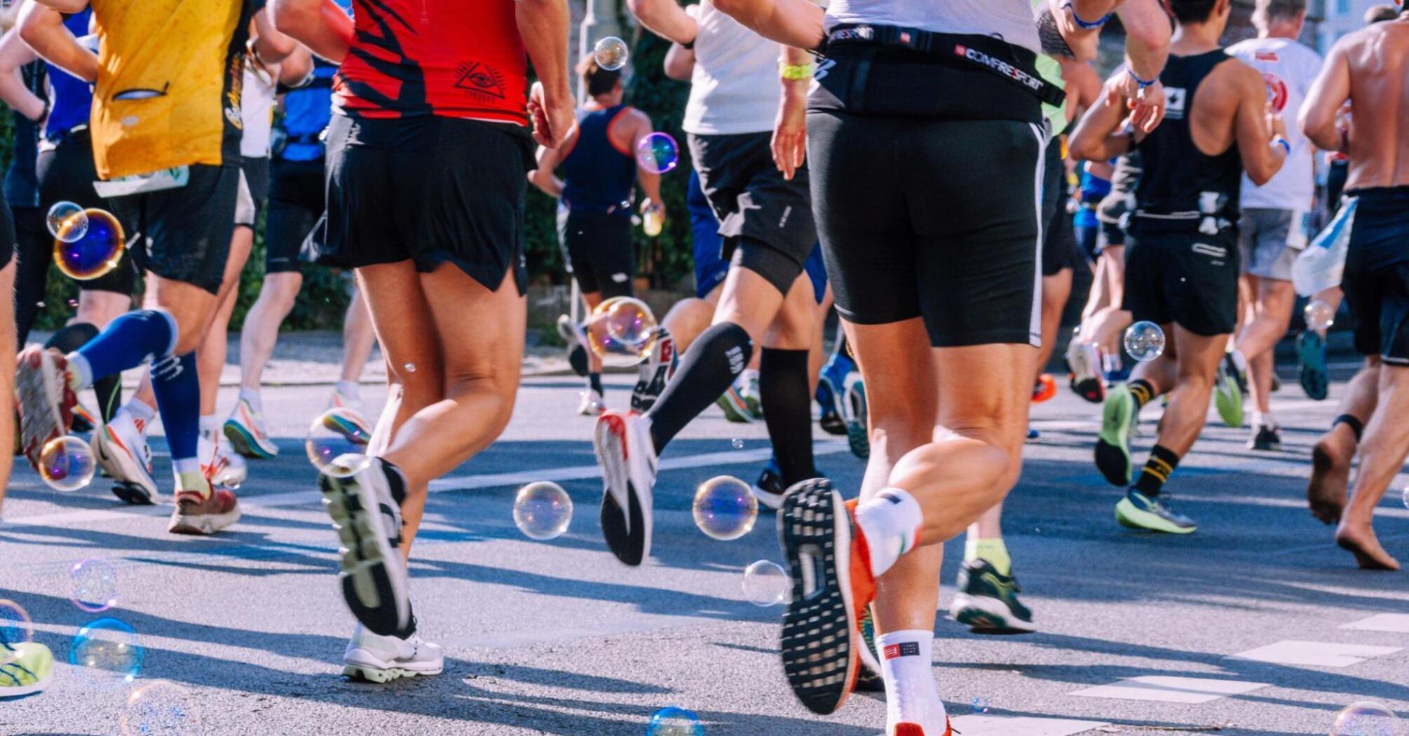 Marathon participants running on city streets with bubbles adding a festive touch