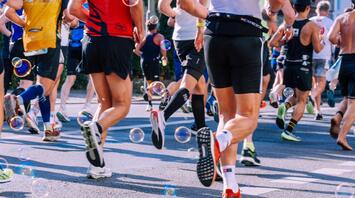 Marathon participants running on city streets with bubbles adding a festive touch