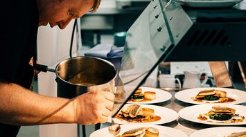 A chef carefully plating gourmet dishes in a professional kitchen