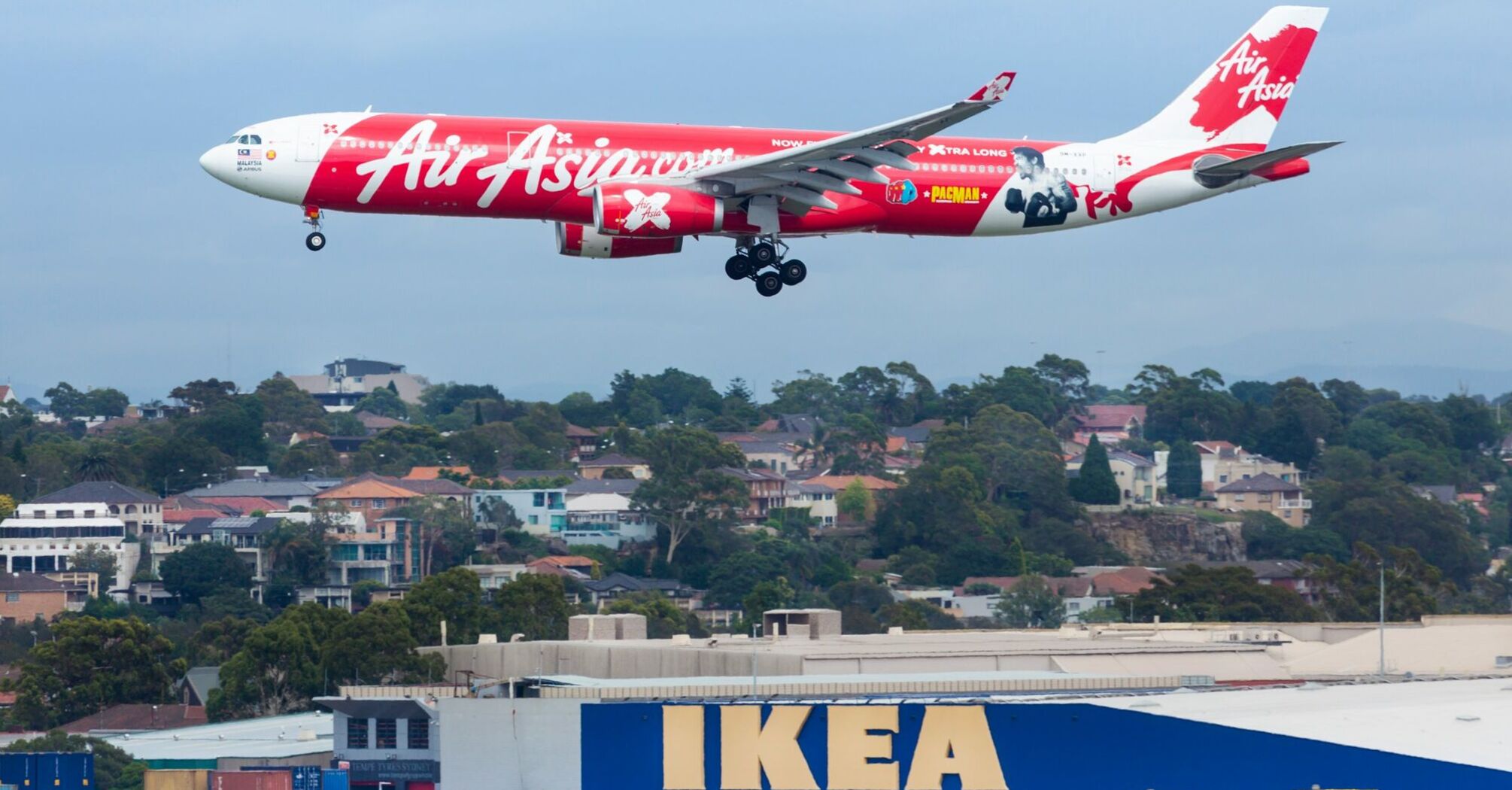 AirAsia plane landing at Sydney Airport with IKEA store in the background