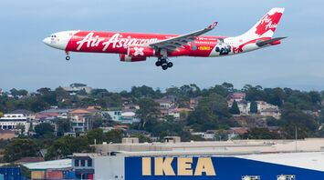 AirAsia plane landing at Sydney Airport with IKEA store in the background