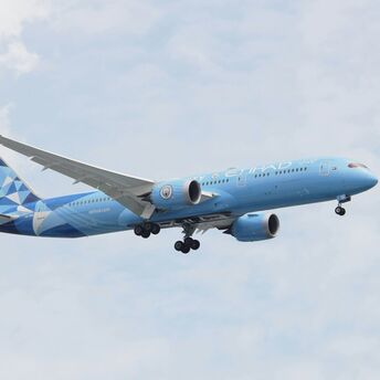 a blue and white airplane flying in the sky