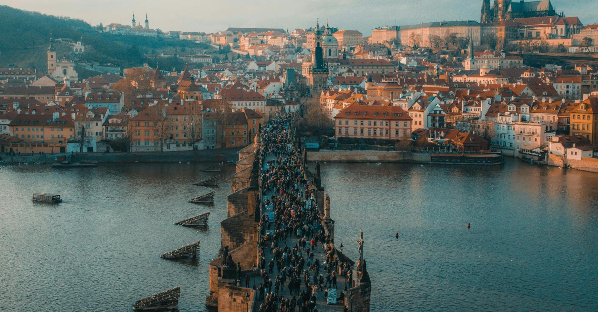 Aerial view of Charles Bridge crowded with tourists and Prague Castle in the background