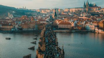 Aerial view of Charles Bridge crowded with tourists and Prague Castle in the background