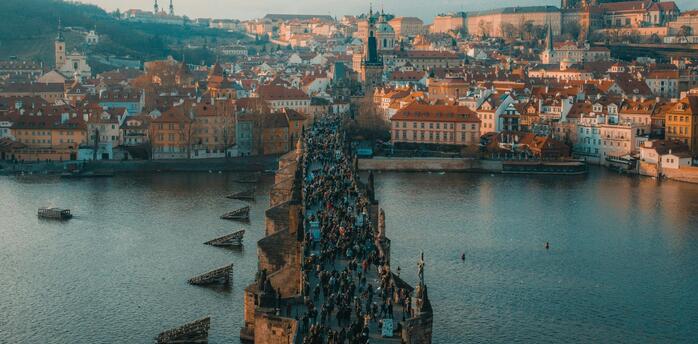 Aerial view of Charles Bridge crowded with tourists and Prague Castle in the background