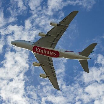 Emirates aircraft flying against a blue sky with clouds